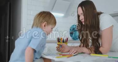 妈妈帮儿子<strong>学画</strong>做作业学前准备在家坐在白色厨房..
